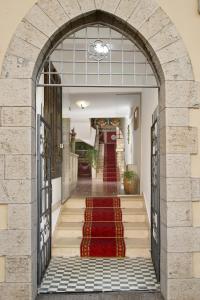 un arco che conduce a un edificio con tappeto rosso di Hotel Porta Marmorea a Gubbio