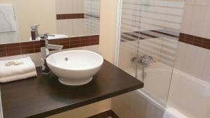 a bathroom with a white sink and a shower at Auberge de Cartassac in Sarrazac