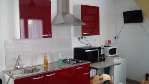 una cucina con armadi rossi, lavandino e forno a microonde di Gîte de Blessy a Blessy