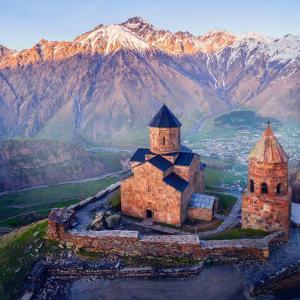 an old church on a hill with mountains in the background at Guest House Dodo in Stepantsminda