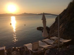 a group of chairs and an umbrella in front of the water at Rosys Little Village in Skala