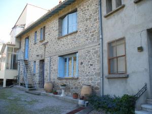 a stone house with blue windows and a staircase at Petite Maison de Village in Corneilla-de-Conflent