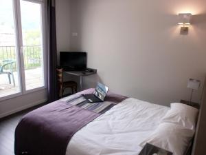 a bedroom with a bed with a laptop on it at Hôtel des Rosiers in Lourdes