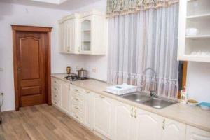 a kitchen with white cabinets and a sink and a window at Pensiunea Maria in Fîrdea