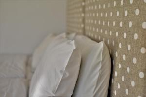 uma cama com lençóis brancos e almofadas em Annis House em Skiathos Town