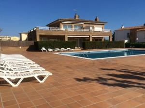 Un grupo de tumbonas blancas junto a una piscina. en Sol Apartment, en L'Estartit