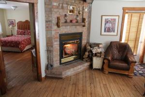 a living room with a brick fireplace and a chair at B&B Les Deux Pignons in Petit-Saguenay