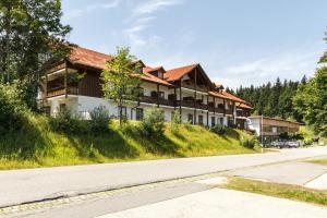 a building on the side of a hill next to a road at 2022 Neu renoviert- Apartments Michaela in Philippsreut