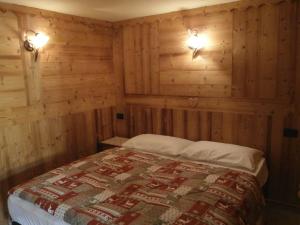 a bedroom with a bed with wooden walls and lights at Petites Fleurs Cogne in Cogne