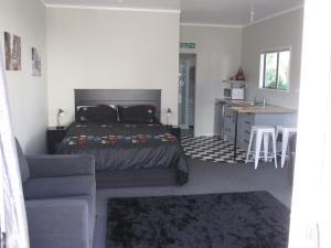 a bedroom with a bed and a couch and a kitchen at Cruz Inn in Featherston