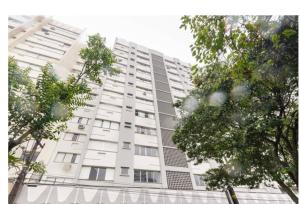 a tall white building with trees in front of it at Top Floripa Apartment in Florianópolis