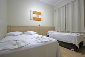a room with two beds with white sheets at Pousada Flores em Vida in Olímpia