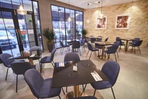 un restaurante con mesas, sillas y ventanas en Corsica Hotel en Kulai