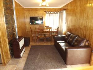 a living room with a leather couch and a table at Cabañas Pulegan in Porvenir