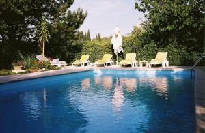 a swimming pool with chairs and a statue next to it at Chambres d'Hôtes Saint Vérédème in Pujaut