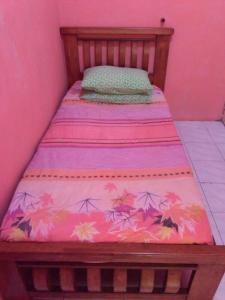a small bed in a room with a pink wall at Deenaz Utara Homestay in Alor Setar