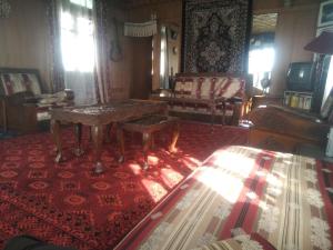 a living room with a table on a red rug at SnowGoose Group of Houseboats in Srinagar