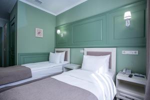 2 Betten in einem Zimmer mit grünen Wänden in der Unterkunft Grand Sapphire Hotel in Almaty