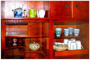 un armario de madera lleno de tazas y jarrones en Casa Sanpond, en Kanazawa