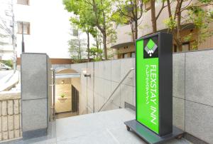 東京にあるフレックステイイン巣鴨の建物横の緑黒看板
