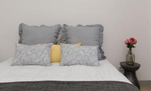 Una cama con almohadas grises y un jarrón con una flor en Rising Sun, en Lisboa