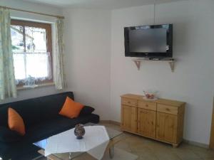 ein Wohnzimmer mit einem Sofa und einem TV an der Wand in der Unterkunft Sägehof in Neustift im Stubaital