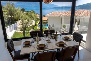 ein Esszimmer mit einem Tisch und Stühlen sowie einem großen Fenster in der Unterkunft White Olive Villa in Herceg-Novi