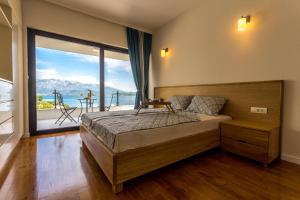 sypialnia z łóżkiem i dużym oknem w obiekcie White Olive Villa w mieście Herceg Novi