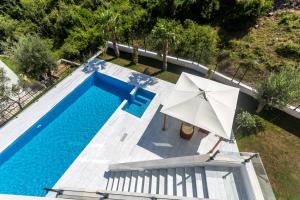 an overhead view of a swimming pool with an umbrella at White Olive Villa in Herceg-Novi
