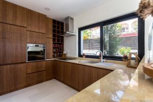 a kitchen with wooden cabinets and a large window at White Olive Villa in Herceg-Novi