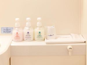 four bottles of moisturizers sitting on a shelf in a bathroom at Hotel Roco Inn Okinawa in Naha
