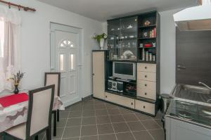 a kitchen with a tv in a cabinet and a table at Zora Apartment in Mali Lošinj