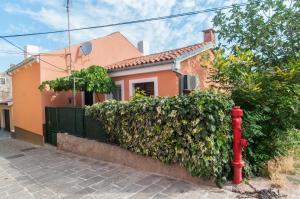 a red fire hydrant in front of a house at Zora Apartment in Mali Lošinj