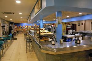 a restaurant with a long counter with tables and chairs at Hotel Royal III in Pesués