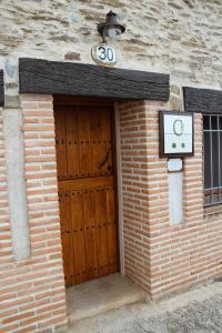un edificio de ladrillo con una puerta de madera con una señal en Casa Rural El Quinto y Medio, en Valdelacasa de Tajo