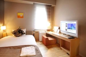 a bedroom with a bed and a desk with a television at Hotel Gracery Tokyo Tamachi in Tokyo