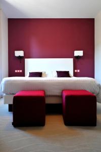 a bedroom with a large bed with a red wall at Logis- Hôtel Spa Restaurant l'Epicurial in Saint-Pey-de-Castets