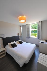 een slaapkamer met een groot wit bed en een raam bij Logis- Hôtel Spa Restaurant l'Epicurial in Saint-Pey-de-Castets