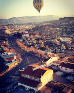 Ein Heißluftballon fliegt über eine Stadt in der Unterkunft Hotel Ozyel in Ortahisar