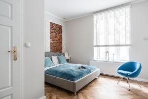 a bedroom with a bed and a blue chair at Apartments Factory in Sopot