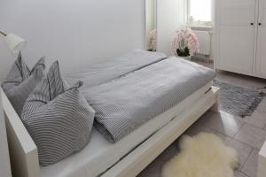 ein Bett mit schwarzen und weißen Kissen in einem Schlafzimmer in der Unterkunft Reiterhof an der Nordsee in Witzwort