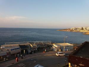 ein weißer Van auf einem Parkplatz neben dem Meer geparkt in der Unterkunft Panorama Mediterranea in St Paul's Bay