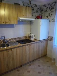 cocina con armarios de madera, fregadero y nevera en Kalbakas Apartamenti en Smiltene