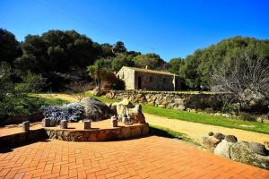 um jardim com um pátio de tijolos com pedras e uma casa em Lu Rotu em Sant'Antonio di Gallura