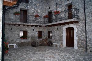 a stone building with a balcony and two benches at Hostal Rural Casa Parda in Tramacastilla de Tena