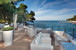 un patio con muebles blancos y vistas al agua en Apartments Galijot Plava Laguna en Poreč