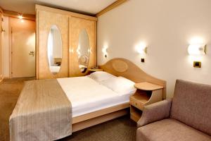 sypialnia z łóżkiem, krzesłem i lustrem w obiekcie Hotel Istra Plava Laguna w Poreču
