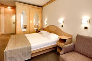 a bedroom with a bed and a chair and a mirror at Hotel Istra Plava Laguna in Poreč