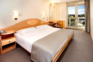 a hotel room with a large bed and a window at Hotel Istra Plava Laguna in Poreč