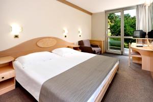 a hotel room with a large bed and a desk at Hotel Istra Plava Laguna in Poreč